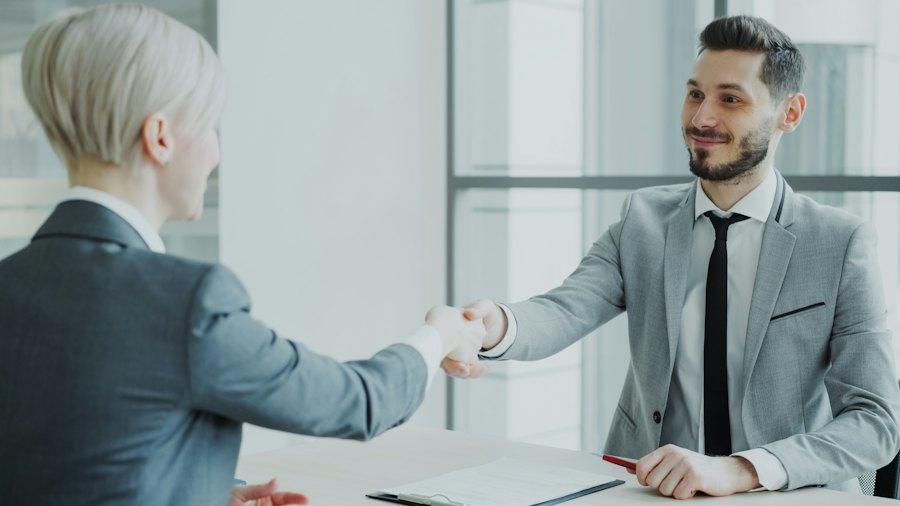 Two professionals shaking hands across a desk